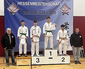 Fünf junge Judoka stehen auf dem Siegertreppchen bei der Hessenmeisterschaft 2025. Die ersten drei Platzierungen sind mit Medaillen ausgezeichnet, während die Teilnehmer ihre Urkunden halten. Im Hintergrund hängt ein Banner mit dem Titel der Meisterschaft.